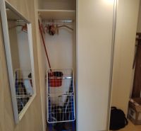 Vestavěná skříň s posuvnými dveřmi, věšáky a zrcadlo v 2-pokojovém bytě.