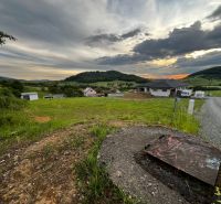 Pozemky - bydlení ve Stožku se scenérií zeleně a venkovskými domy při západu slunce.
