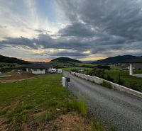 Panoráma obce Stožok se západem slunce a pozemky na bydlení v kopcovité krajině.