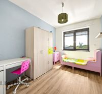 Dětský pokoj s postelí, skříní, psacím stolem a podlahou s dřevěným dekorem.