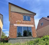 Rodinný dům v Cerové s nedokončenou cihlovou fasádou a velkými prosklenými dveřmi.