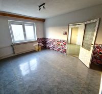 Pokoj v rodinném domě s dekorovanou stěnou a velkým oknem, podlaha s dřevěným dekorem.