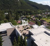 Pohled na střešní terasu mezi budovami obklopenými přírodou v Rajeckých Teplicích na ulici M. R. Štefánika.