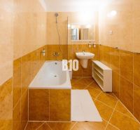 Koupelna v rekreačním apartmánu s vanou, umyvadlem a světlými obklady.