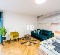 Stylový rekreační apartmán s podlahou s dřevěným dekorem, pohovkou a rostlinami.