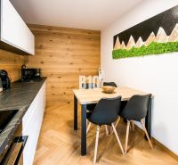 Interiér rekreačního apartmánu s kuchyní, jídelním stolem a podlahou s dřevěným dekorem.