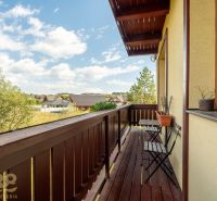 Balkon 2-pokojového bytu s dřevěným obložením ve Velké Lomnici, výhled na okolní krajinu.