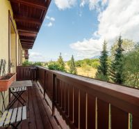 Balkon 2-pokojového bytu ve Velké Lomnici s výhledem na přírodu a stromy.