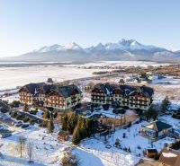 Zimní scenérie ve Velké Lomnici s výhledem na Tatry a budovy, nabízející 2-pokojové byty.