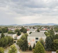 Pohled na Komenského ulici v Trebišově s budovami a zelení.
