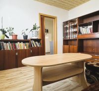 Obývací pokoj se skříněmi, knihami, květinami a podlahou s dřevěným dekorem ve 4pokojovém bytě.