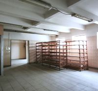 Výrobní prostory s regály a výtahem, osvětlené okny, s keramickou podlahou.