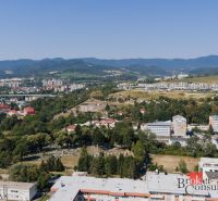 Pohled na panorama Banské Bystrice z Komenského, vidět rodinné domy a přírodu.