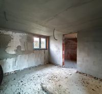 Stavební interiér rodinného domu s nedokončenou omítkou a betonovou podlahou.