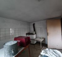 Pokoj v rodinném domě se stolem, kbelíkem a obklady na stěně.