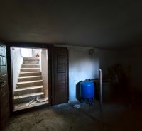 Zahradní sklad v rodinném domě s betonovými schody a modrým zásobníkem.