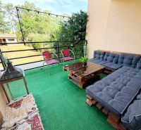 Balkon rodinného domu s paletovým posezením, zeleným kobercem a výhledem na zahradu.