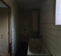 Koupelna s vanou a kachličkami v rodinném domě. Na stěně jsou viditelná poškození.