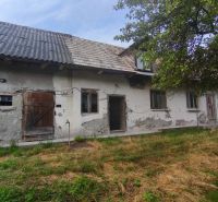 Rodinný dům v Čelovcích s opotřebovanou omítkou, dřevěnými dveřmi a zahradou.