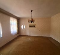 Interiér rodinného domu s kobercovou podlahou, světlem a záclonami na oknech.