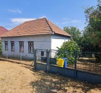Rodinný dům v Dolních Otrokovicích s plotem a zahradou na slunném pozemku.