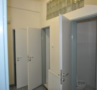 Otevřené dveře na toaletě ve výrobních prostorách s dlažbou a umyvadlem.
