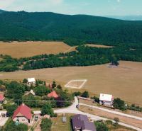 Venkovský pohled na pozemky k bydlení v Podhradí obklopené lesy a loukami.