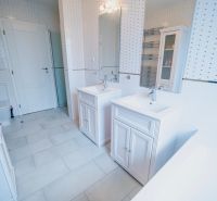 Koupelna se dvěma umyvadly, vanou a dlažbou v rodinném domě.