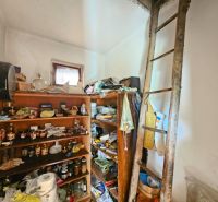 Police s potravinami a žebřík v místnosti rodinného domu.