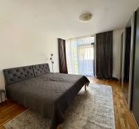 Ložnice ve 4pokojovém bytě s podlahou s dřevěným dekorem, velkou postelí a šatní skříní.