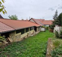 Zahrada u rodinného domu v Mokrém Háji s kamennou zdí a červenou střešní krytinou.