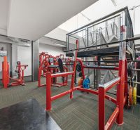 Posilovací stroje a lavice, jasné osvětlení, obchodní prostory se sportovním vybavením.