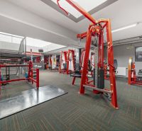 Fitness centrum s činkami a posilovacími stroji, obchodní prostory.
