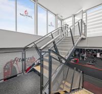 Ocelové schodiště v dvoupodlažních obchodních prostorách s fitness zařízeními.
