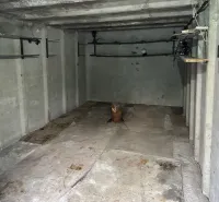 Interiér garáže s betonovými stěnami a policemi na ukládání věcí.