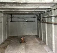 Prázdný betonový interiér garáží s policemi a osvětlením.