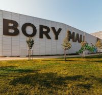 Nákupní centrum Bory Mall s nápisem, travnatá plocha a stromy v Bratislavě-Lamači.
