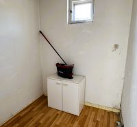 Malá místnost s oknem, skříní a podlahou s dřevěným dekorem v rodinném domě.