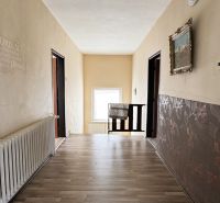 Chodba v rodinném domě s podlahou s dřevěným dekorem, ozdobnými stěnami a radiátorem.