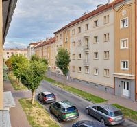 Ulice Študentská ve Zvolenu s bytovými domy a projíždějícími auty, vhodná pro garsonku.