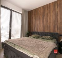 Dvojlůžková postel s měkkou přikrývkou v 2-pokojovém bytě s podlahou s dřevěným dekorem.