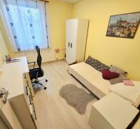 Žlutý pokoj s jedním lůžkem, pracovním stolem a podlahou s dřevěným dekorem ve 4pokojovém bytě.