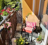 Balkon 3pokojového bytu s pohodlným sezením, květinami a výhledem na zeleň.