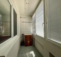 Zasklený balkon s dřevěnou skříňkou a sušákem, součást garsonky.