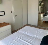 Ložnice v 2-pokojovém bytě s bílou postelí a podlahou s dřevěným dekorem.