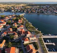 Letecký pohled na pobřežní oblast města Nin se střechami vil a přístavem.