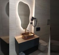 Koupelna s moderním světlem, zrcadlem a designovým umyvadlem ve vile.