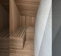 Sauna v interiéru vily s dřevěným obkladem a lavicemi.