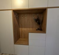 Bílá vestavěná skříň s dřevěným dekorem a věšáky v 2-pokojovém bytě.