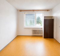 Prázdná místnost s podlahou s dřevěným dekorem, šatní skříní a radiátorem v 2-pokojovém bytě.